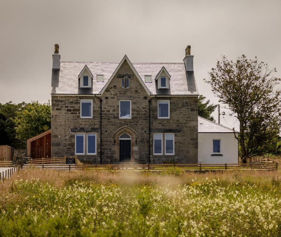 uma velha casa de pedra num campo de flores em House of Juniper em Broadford