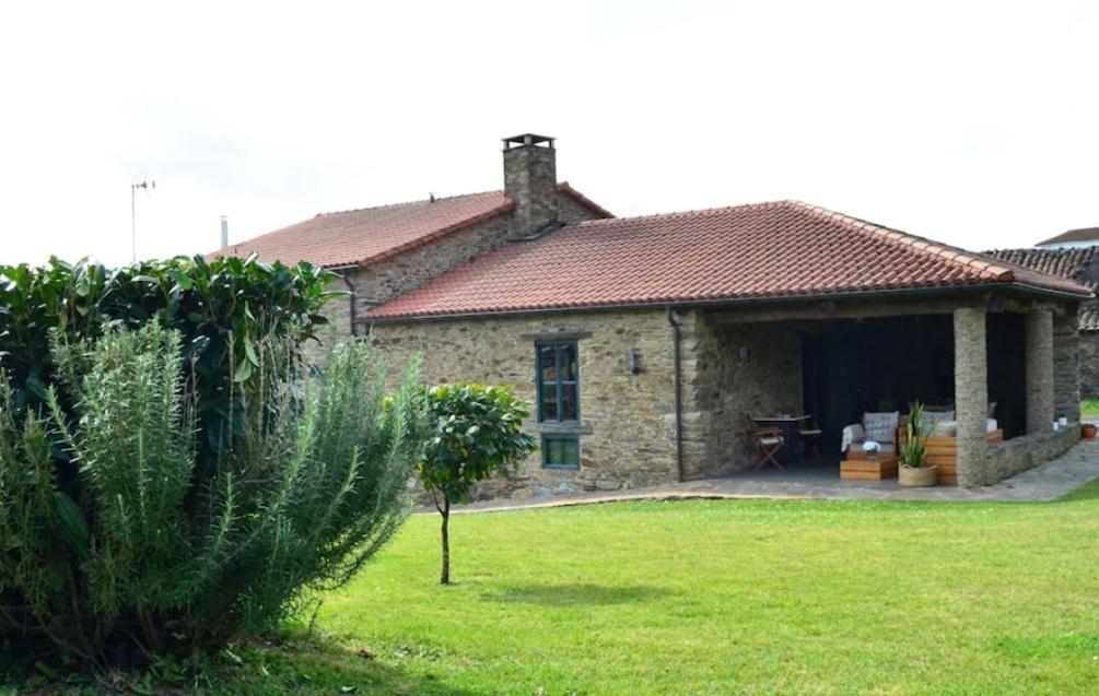 una casa de piedra con un gran patio delante en Fogar de Lecer, en Arzúa