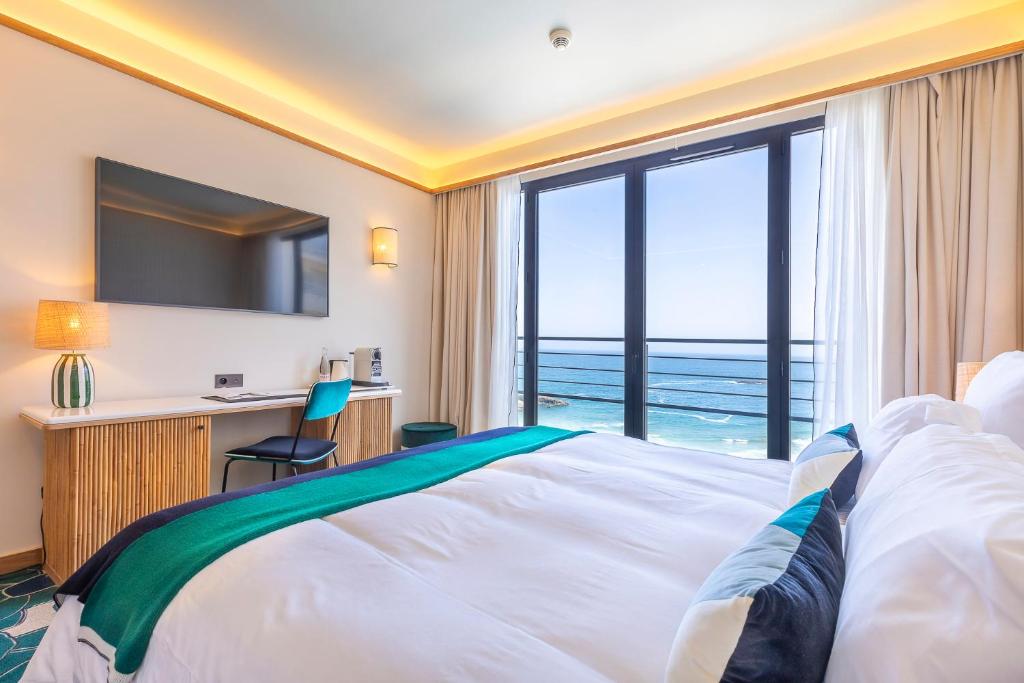 a hotel room with a bed and a view of the ocean at Hôtel Le Café de Paris in Biarritz