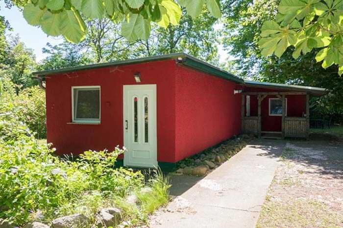 ein rotes Haus mit einer weißen Tür im Hof in der Unterkunft Ferien im Gutspark Schwarbe mit Re in Mattchow