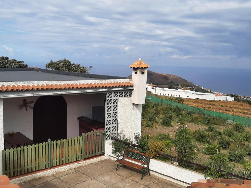 una pequeña casa blanca con un banco y una colina en Casa rural en finca ecológica, en La Orotava
