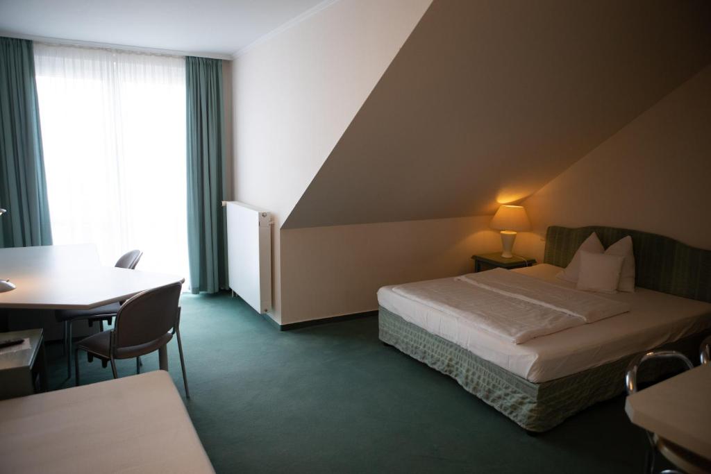 Habitación de hotel con cama, escritorio y mesa. en pepb Schulungshotel, en Sarstedt