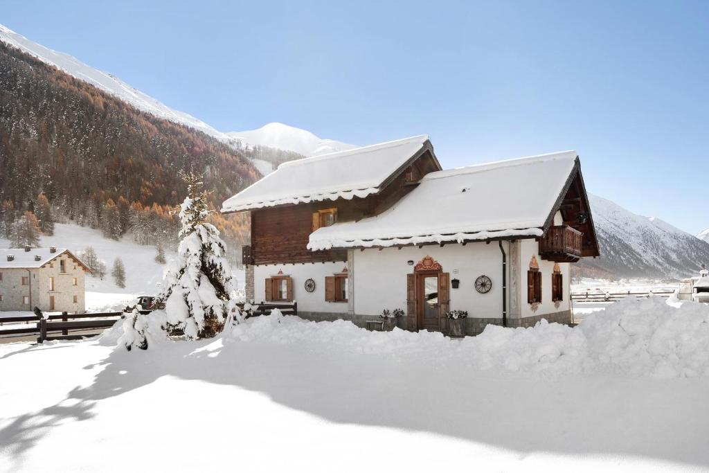 a house covered in snow in front of a mountain at Baita sulle Alpi in Livigno