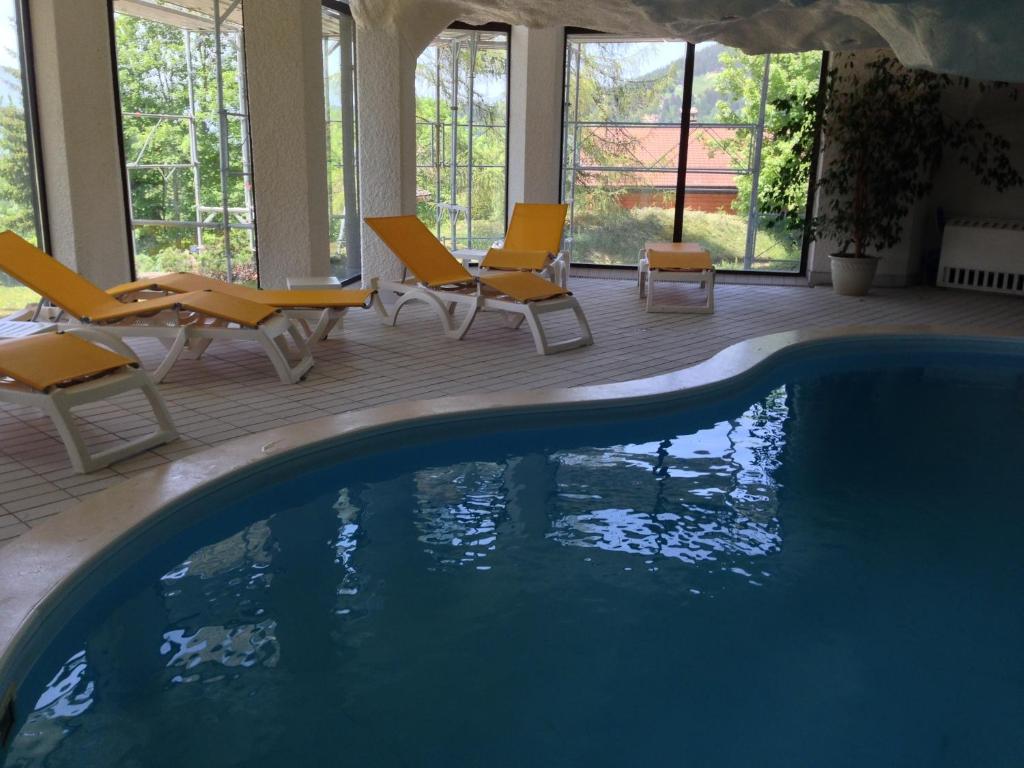 a swimming pool with chairs and a swimming pool at Le Bristol - Villars Bristol Apartments in Villars-sur-Ollon