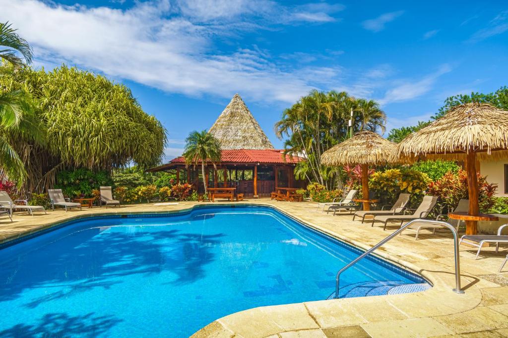 a pool at a resort with chairs and umbrellas at Guacamaya Lodge in Paraíso