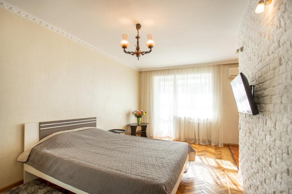 a bedroom with a bed and a large window at Уютная квартира в центре in Mykolaiv