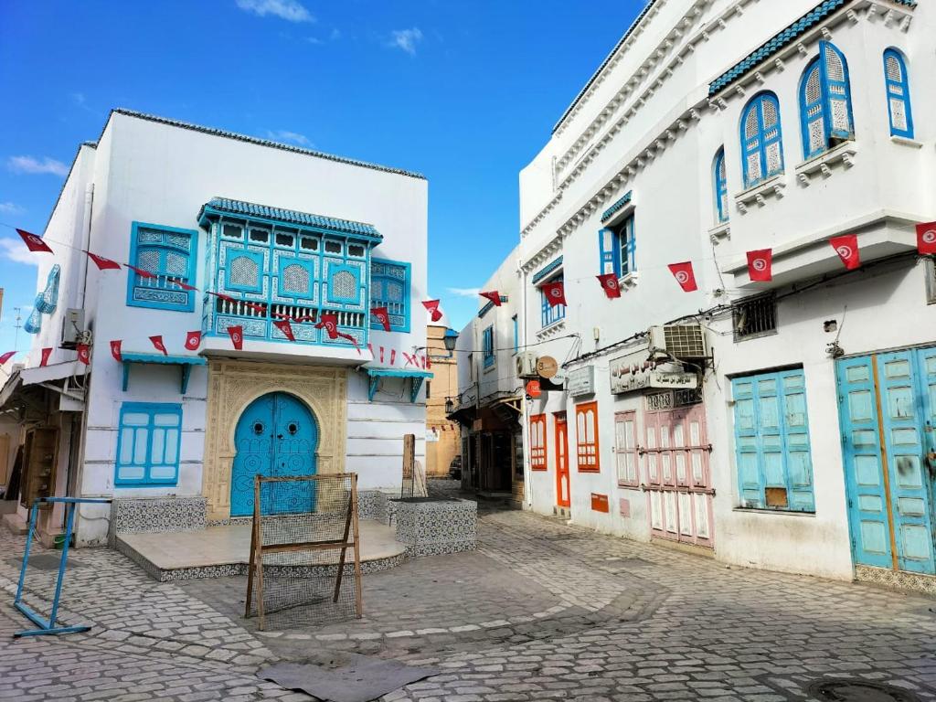 a street with white buildings and blue doors at Maison d'hôte Chama in Kairouan