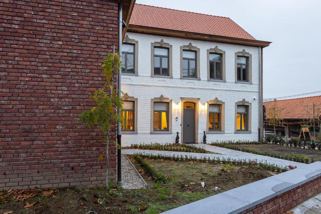 una casa bianca con porte gialle e un edificio in mattoni di 't Verschil a Etikhove