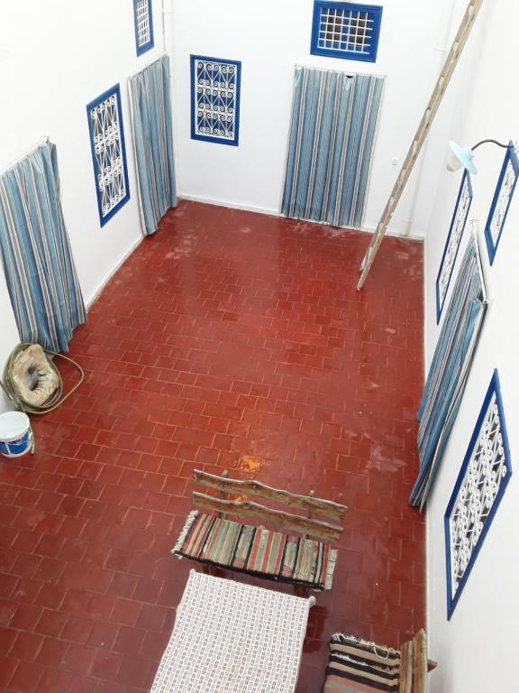 an empty room with a red brick floor with a bench at Maison d'hôte Chama in Kairouan