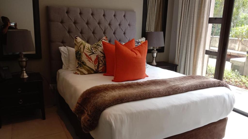 een slaapkamer met een groot bed met oranje kussens bij Zimbali Suites 223 in Ballito