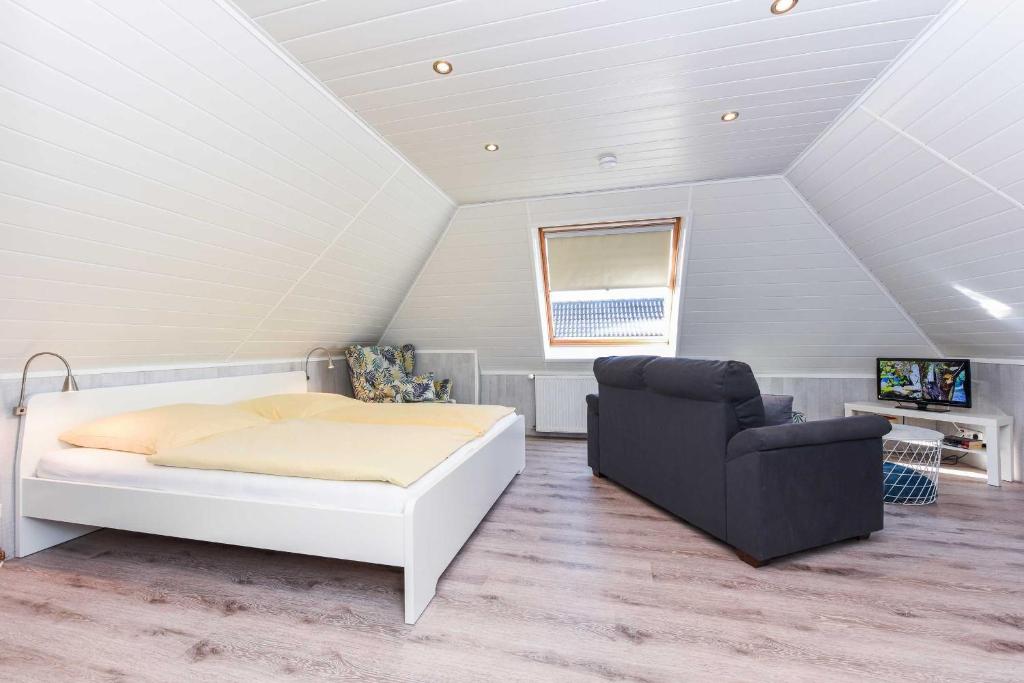 a bedroom with a bed and a chair in a attic at Haus Windliese Apartments in Bensersiel