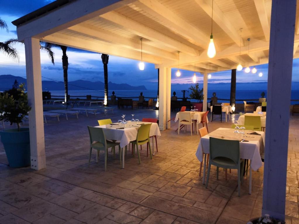 a restaurant with tables and chairs on a patio at night at Petruso Resort in Balestrate
