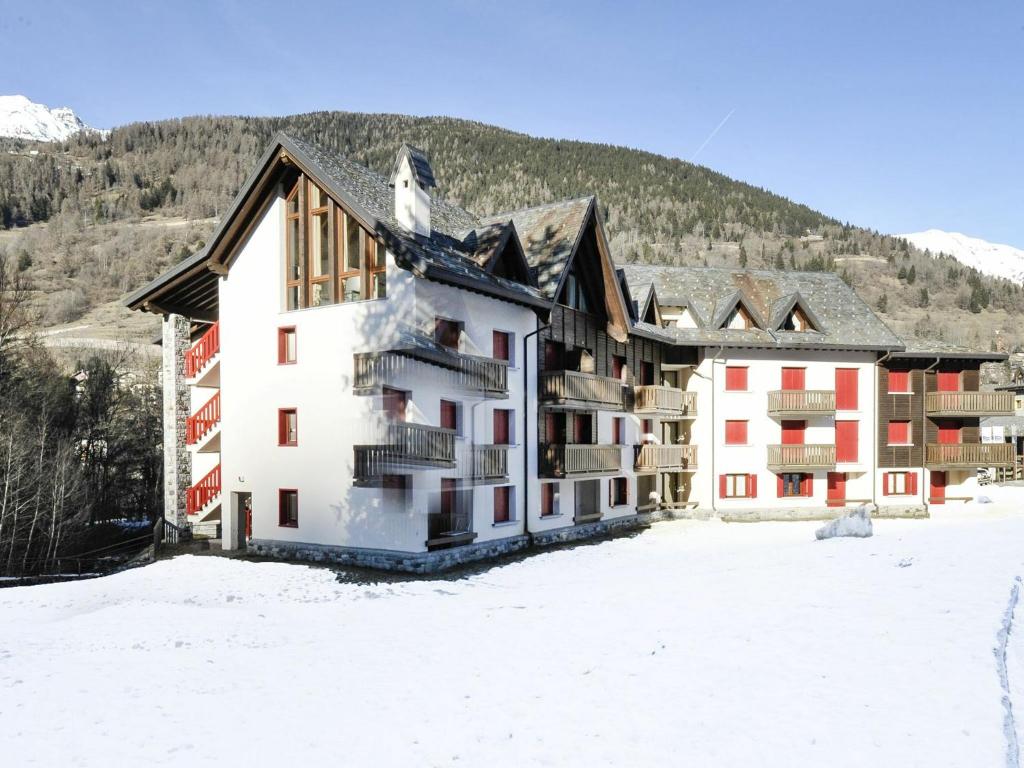a building in the snow with a mountain in the background at Residenze Holiday Park in Ponte di Legno