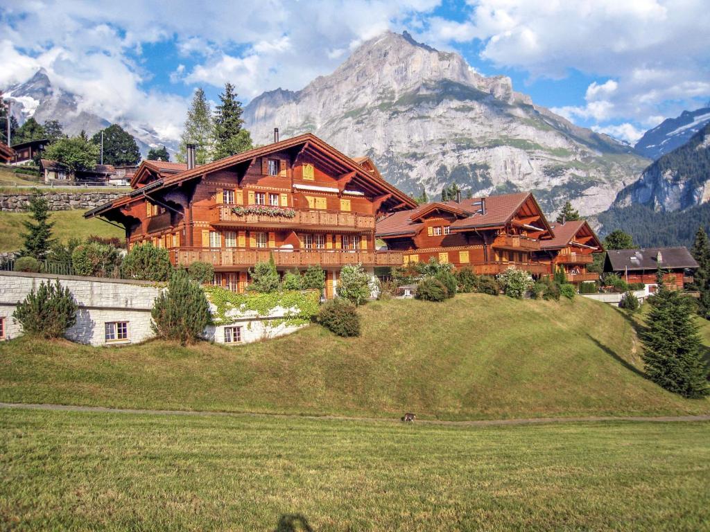 una gran casa de madera en una colina con una montaña en Apartment Chalet Cortina by Interhome, en Grindelwald