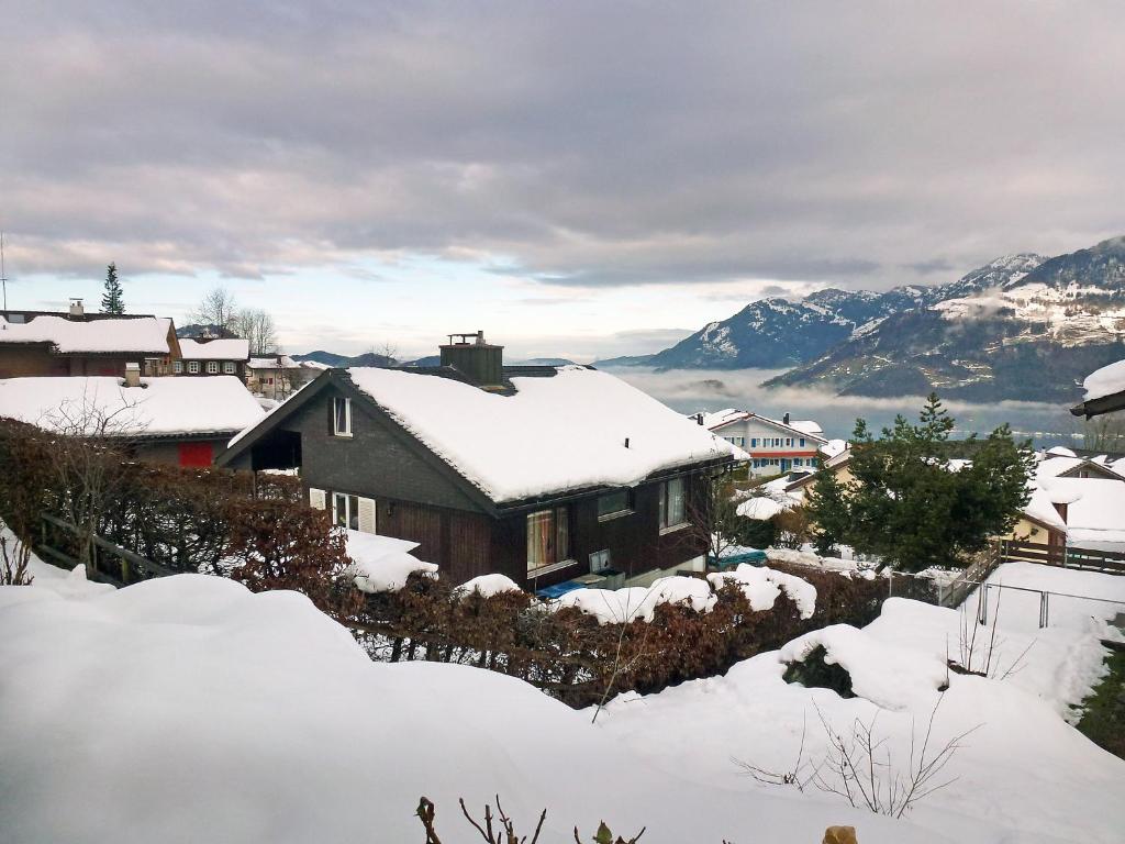 ein schneebedecktes Haus mit Bergen im Hintergrund in der Unterkunft Apartment Mansalo by Interhome in Emmetten