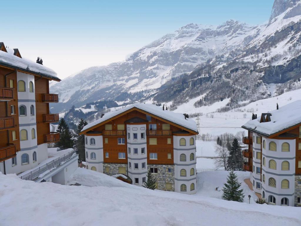 a group of buildings in the snow in front of a mountain at Apartment Edelweiss D by Interhome in Leukerbad