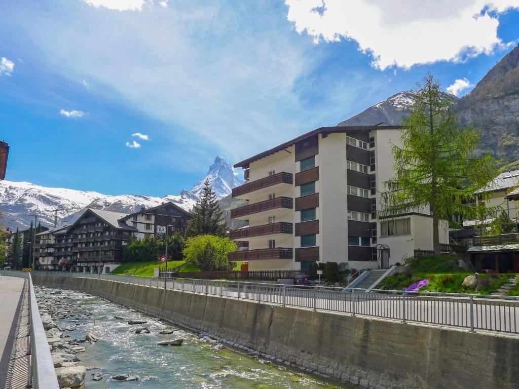 een gebouw naast een rivier met bergen op de achtergrond bij Apartment Matten - Utoring-18 by Interhome in Zermatt