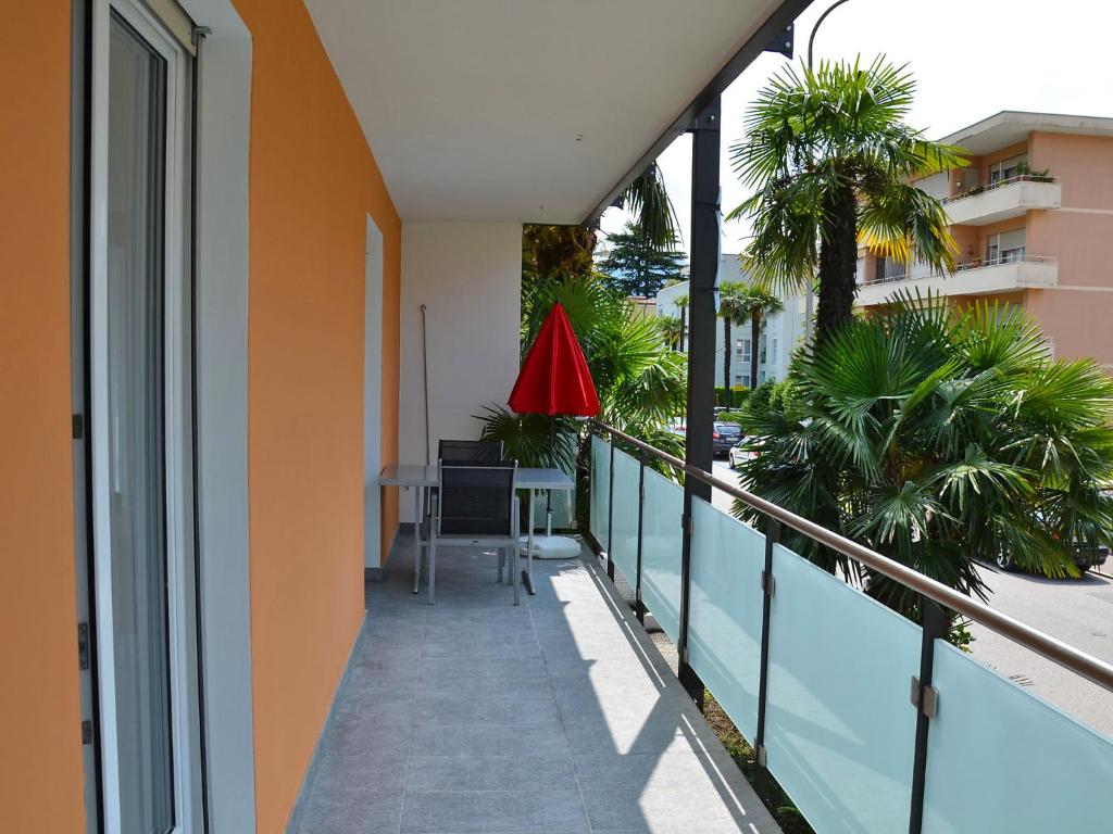 a balcony of a building with a table and palm trees at Apartment Residenza Corallo-22 by Interhome in Ascona