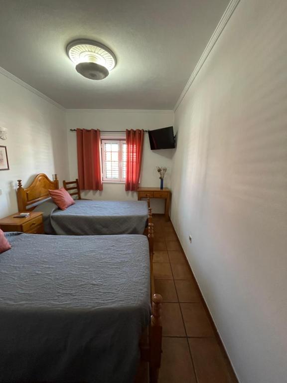 a room with two beds and a television in it at Quartos de Vidigueira in Vidigueira