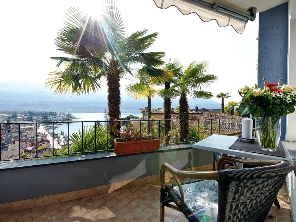 d'un balcon avec une table, des chaises et des palmiers. dans l'établissement Apartment Double Room Classic-10 by Interhome, à Ascona