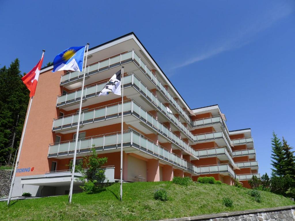 um edifício com bandeiras à sua frente em Apartment Promenade - Utoring-66 by Interhome em Arosa