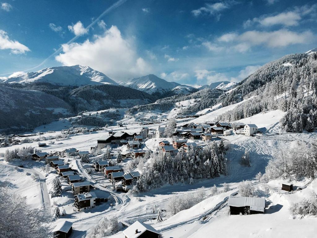 ein schneebedecktes Dorf mit Bergen im Hintergrund in der Unterkunft Apartment Utoring Acletta-75 by Interhome in Disentis