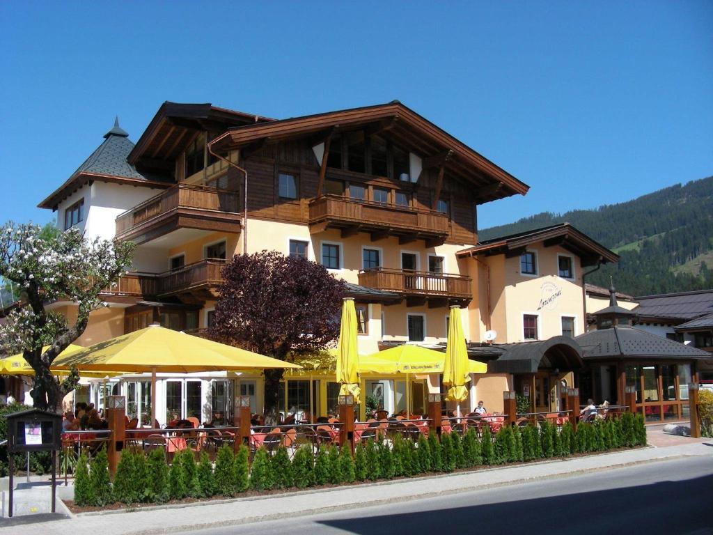 ein Gebäude mit Tischen und Sonnenschirmen davor in der Unterkunft Appartements Lorenzoni, Cafe Konditorei Helmut Lorenzoni in Kirchberg in Tirol