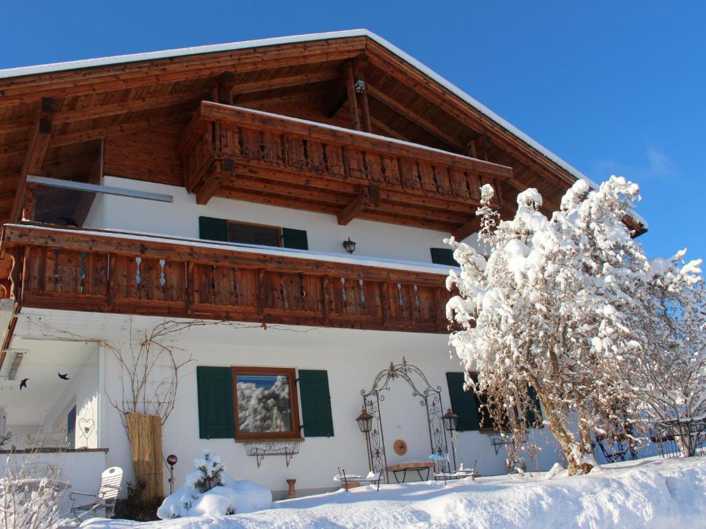 a house with a wooden roof in the snow at Apartment Fischer by Interhome in Lechbruck