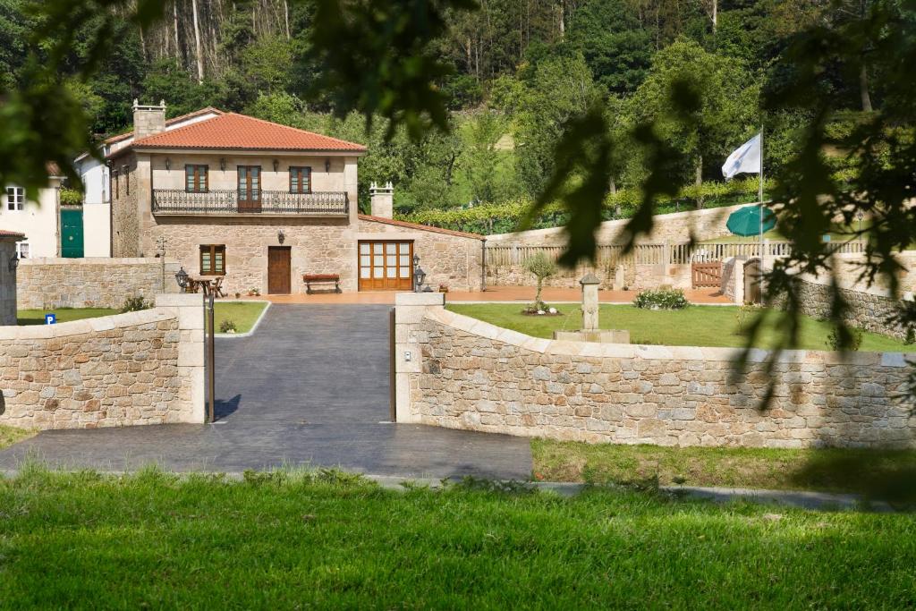 una casa grande con una pared de piedra y un camino de entrada en Casa da Roisa, en Rois