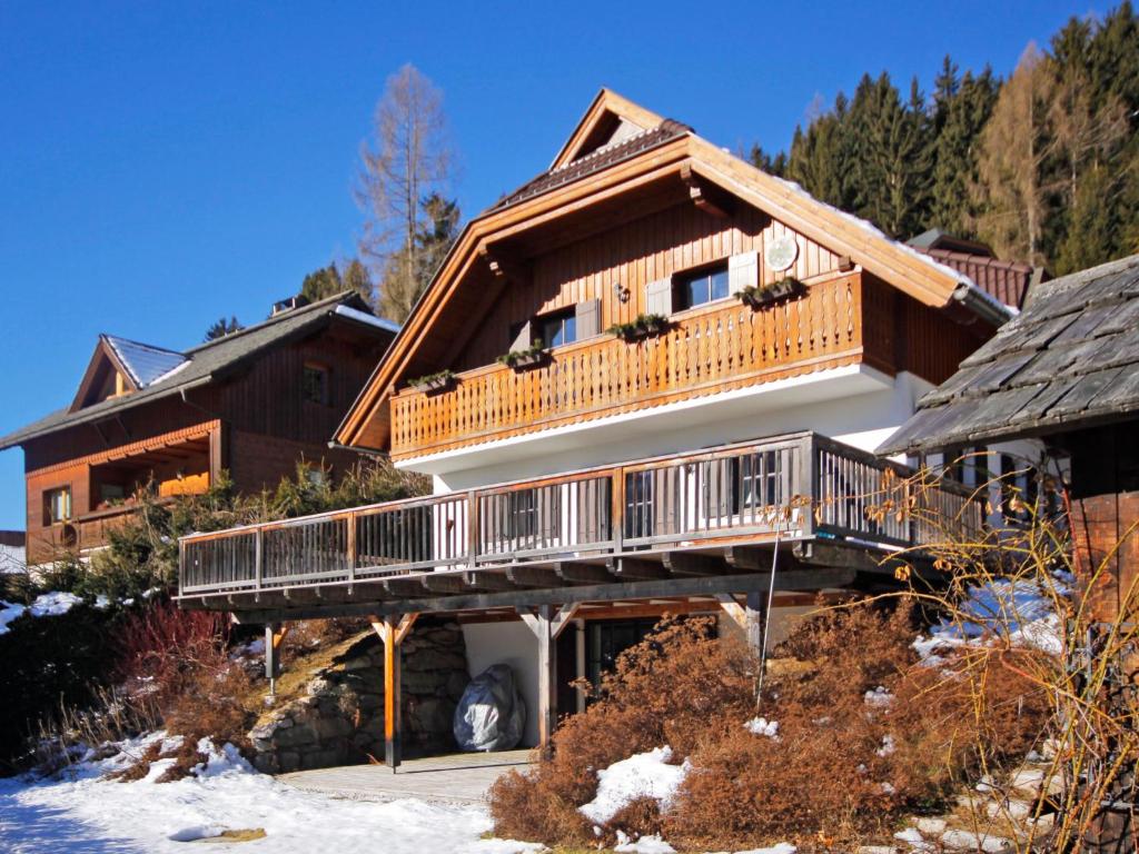 a large log home with a deck on a snow covered yard at Apartment Schwalbennest by Interhome in Bad Kleinkirchheim