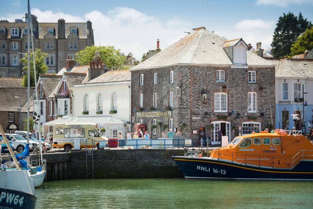 an orange boat is docked in a harbor with buildings at The Old Custom House in Padstow