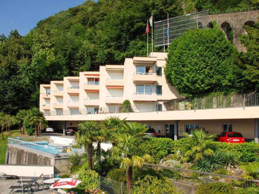 ein Hotelgebäude mit einem Pool und Palmen in der Unterkunft Apartment Aldesago Monte Brè - Utoring-22 by Interhome in Viganello