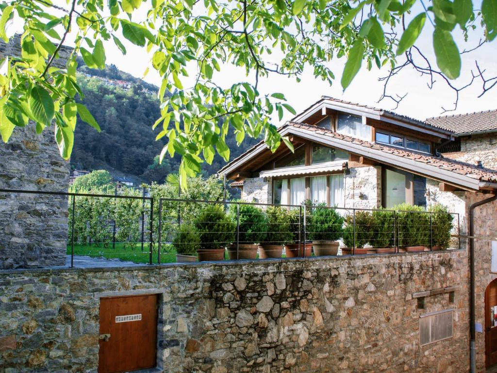 ein Haus mit Topfpflanzen an einer Steinmauer in der Unterkunft Apartment Cantagallo by Interhome in Vernate