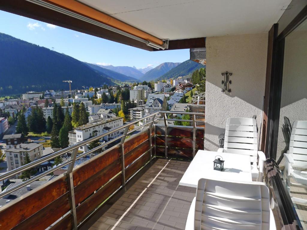 a balcony with white chairs and a view of a city at Apartment Guardaval - Utoring-66 by Interhome in Davos