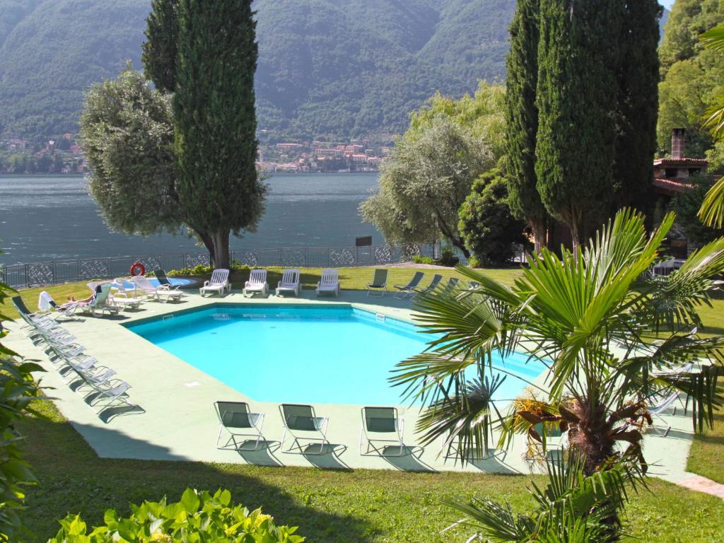 une grande piscine avec des chaises longues et un lac dans l'établissement Apartment La Cava-8 by Interhome, à Pognana Lario