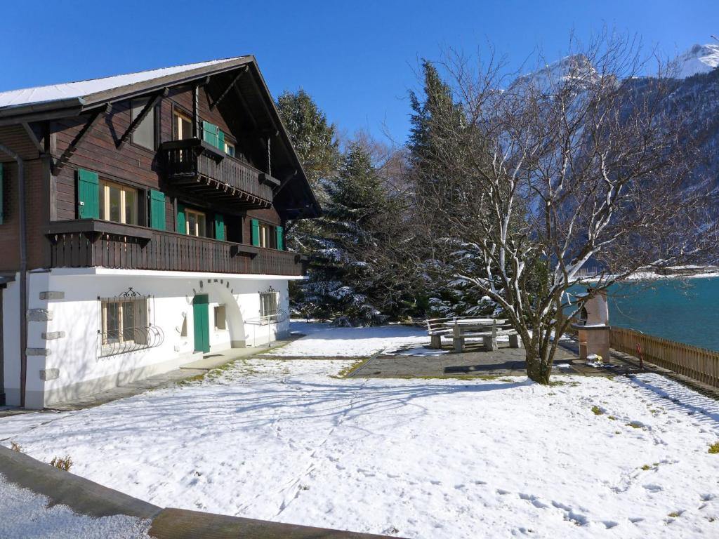 ein Haus mit einem schneebedeckten Hof neben einem Gebäude in der Unterkunft Holiday Home Chalet Aaregg by Interhome in Brienz