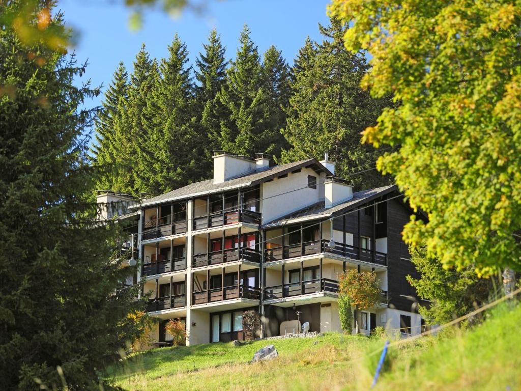 an apartment building on a hill with trees at Apartment Les Petites Maraîches 132-389 by Interhome in Taveyannaz