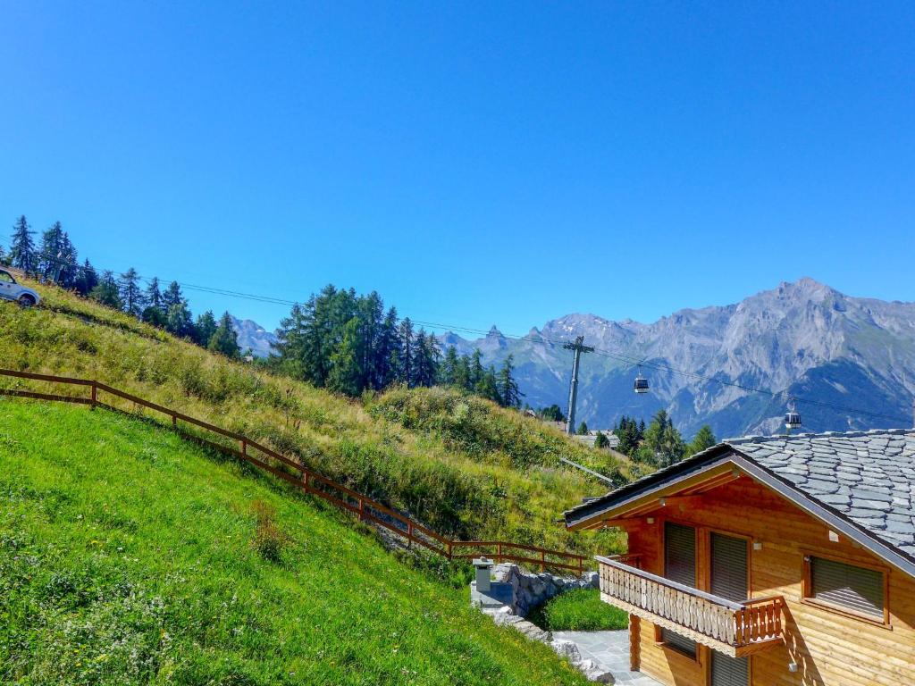 a wooden cabin on a hill with mountains in the background at Chalet Le Ruisseau by Interhome in Nendaz