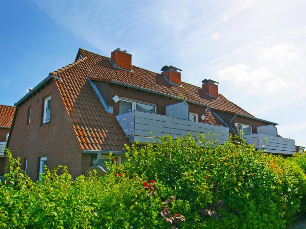 une grande maison brune avec un toit rouge dans l'établissement Apartment Teetied by Interhome, à Norddeich
