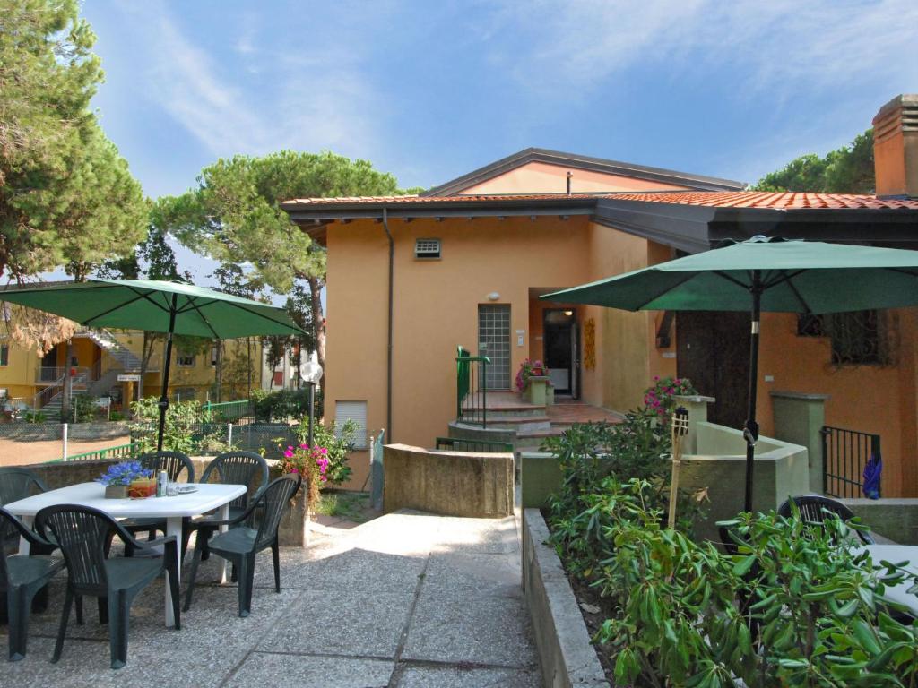un patio con mesas, sillas y sombrillas en Apartment Villa Isotta-3 by Interhome, en Rosolina Mare