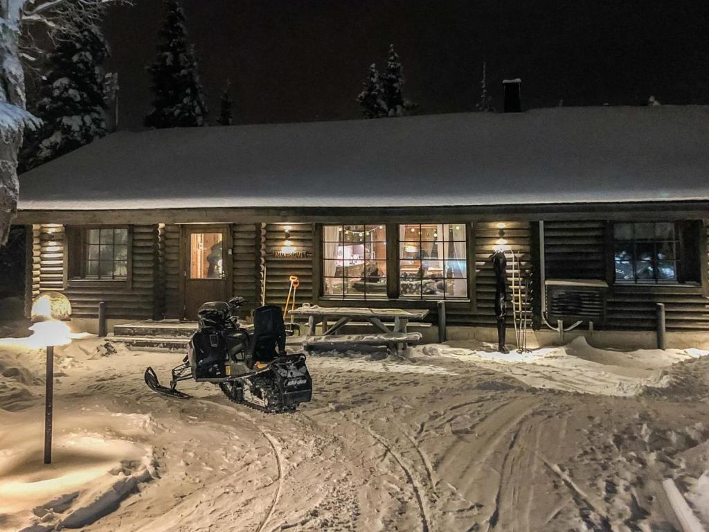 ein Schneemobil, das vor einer Hütte im Schnee geparkt ist in der Unterkunft Holiday Home Huvihovi by Interhome in Ruka