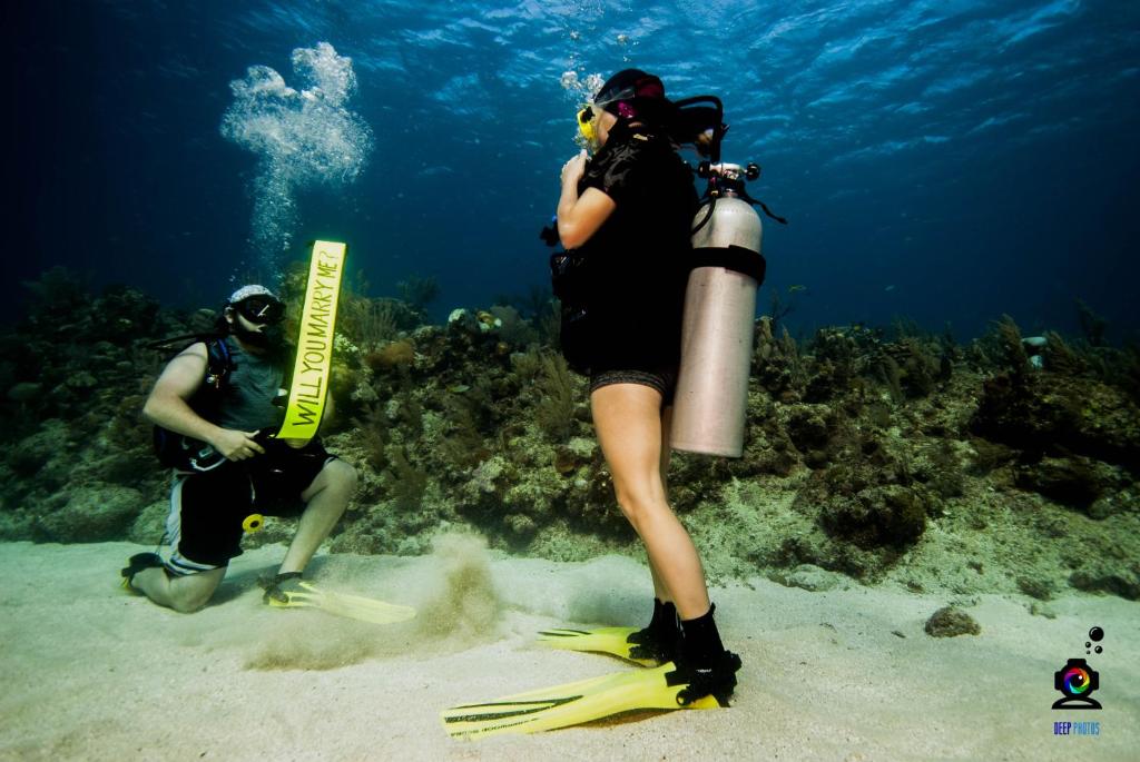 a woman standing in the sand with a snorkeler and a diver at Splash Inn Dive Resort & Villas in West End