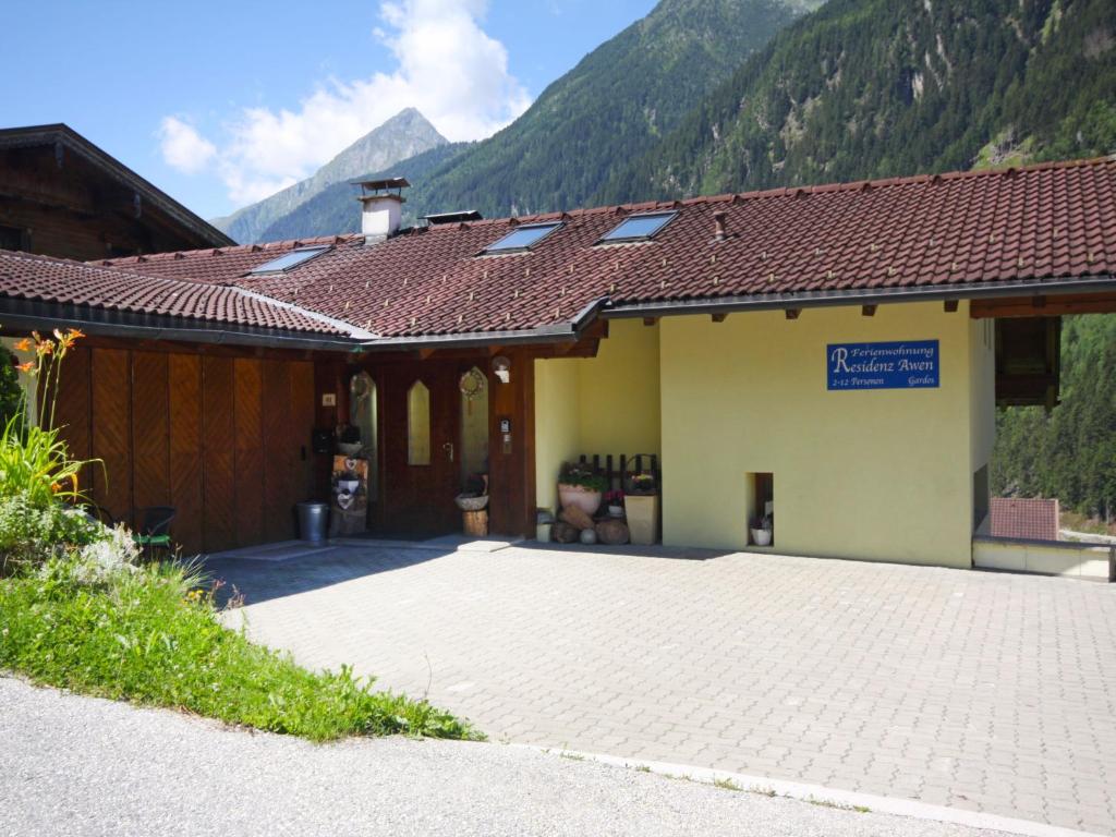 a building with a tile roof with mountains in the background at Apartment Residence Awen-1 by Interhome in Neustift im Stubaital