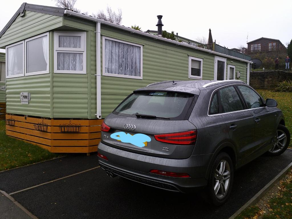 a car parked in a parking lot in front of a house at Superb luxury 2 Bedroom Double bed settee sleep six caravan in Gisburn