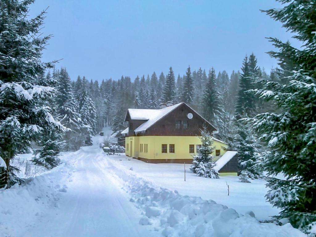 a yellow house in the middle of a snow covered forest at Chalet Karlovka by Interhome in Hrabětice