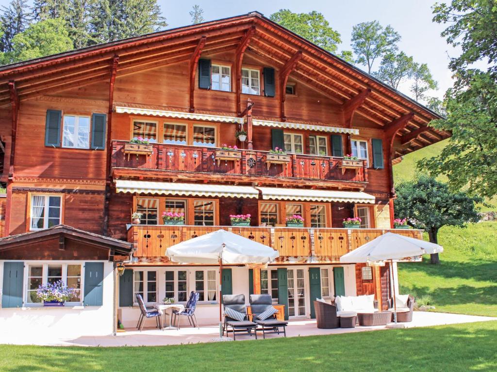 a log house with chairs and umbrellas in front of it at Apartment Chalet Jrene by Interhome in Grindelwald