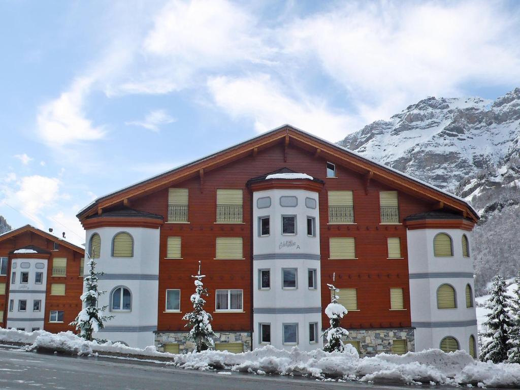 ein großes Gebäude mit verschneiten Bergen im Hintergrund in der Unterkunft Apartment Edelweiss A by Interhome in Leukerbad