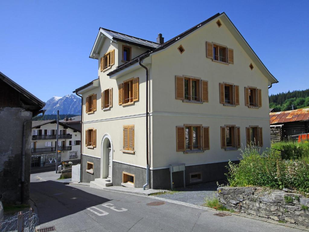 a white house with brown shutters on a street at Apartment Vitg Grond A2 by Interhome in Flims