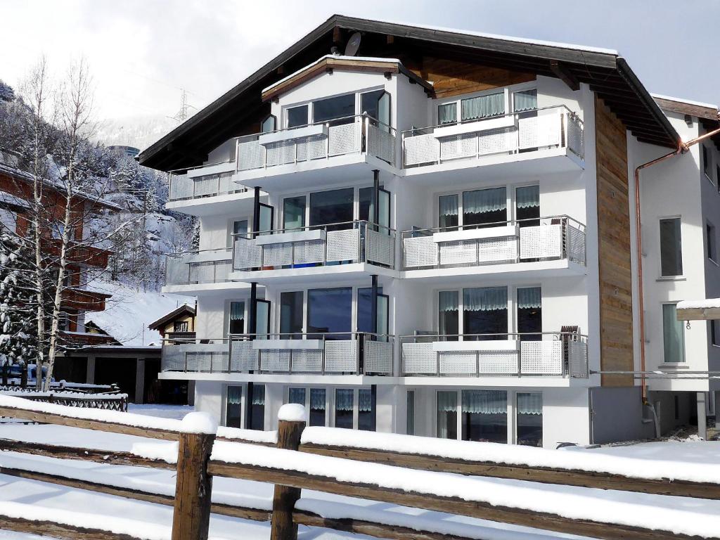 a white building with balconies in the snow at Apartment Amici-1 by Interhome in Saas-Grund