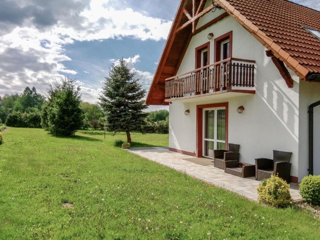 uma casa com uma varanda e um quintal verde em Holiday Home Lgota by Interhome em Witanowice